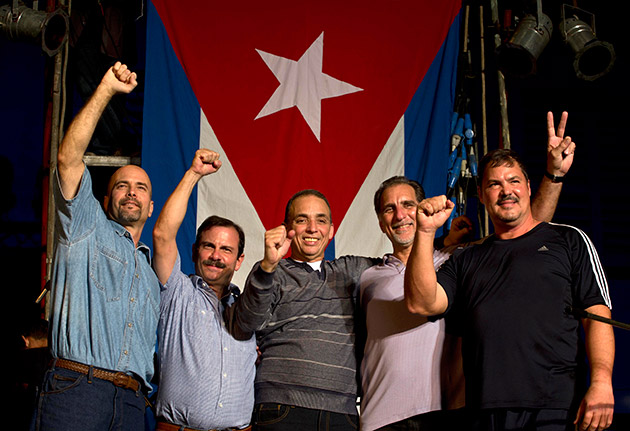 Members of "The Cuban Five," from left,  Gerardo Hernandez, Fernando Gonzalez, Antonio Guerrero, Rene Gonzalez and Ramon Labanino, wave to the public, in front of a Cuban flag after a concert of Silvio Rodriguez in Havana, Cuba, Saturday, Dec. 20, 2014. Guerrero, Labanino, and Hernandez flew back to their homeland on Wednesday in a quiet exchange of imprisoned spies, part of a historic agreement to restore relations between the two long-hostile countries. 