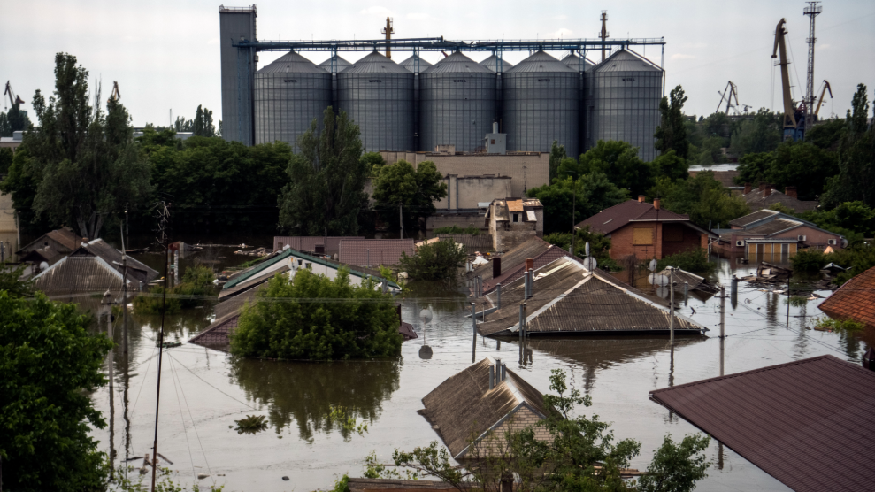 A flooded neighborhood in Ukraine, with brown water reaching the roofs of houses.