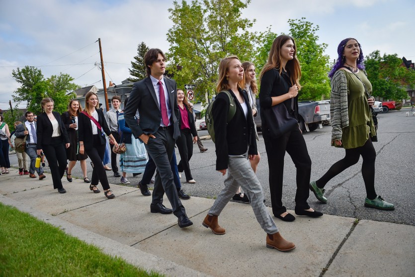 A group of youth of vary ages in business wear walk down a sidewalk.