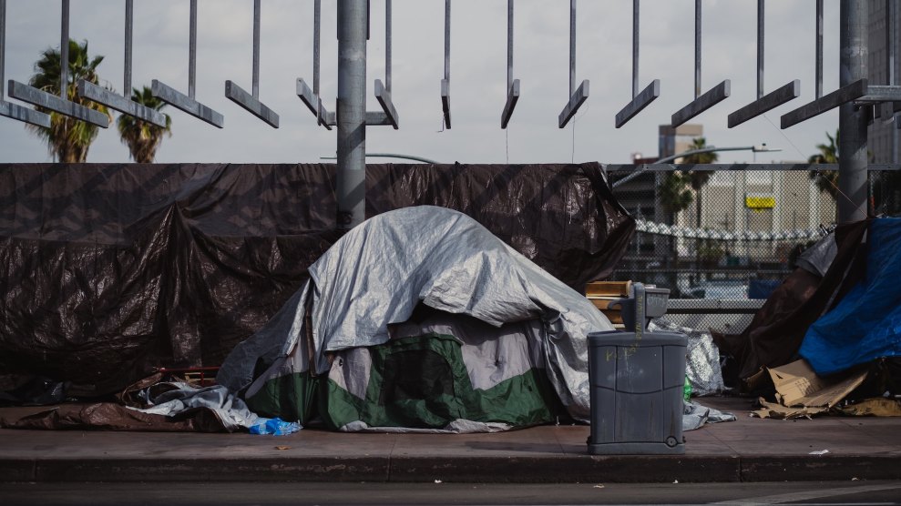 A gray tent with items scattered around it, with a fence in the background