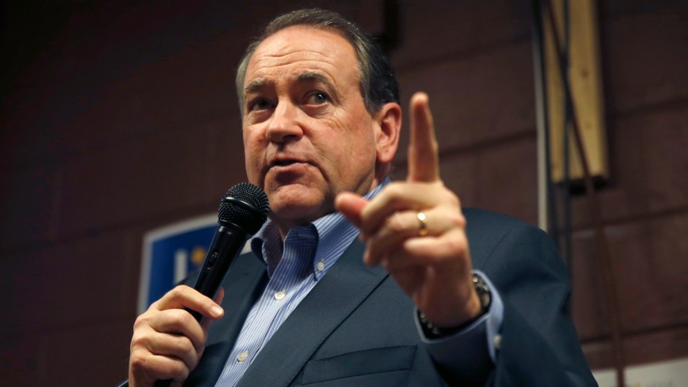 Mike Huckabee, a white man with graying hair in a suit, pointing into the distance while speaking into a microphone