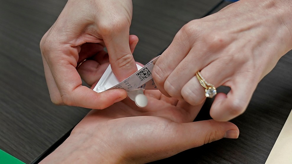 This picture shows a close-up of a woman's hands placing a white pill in another person's palm.