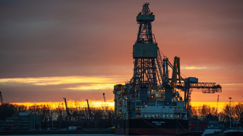 A deep sea mining vessel is silhouetted by an orange sunset.