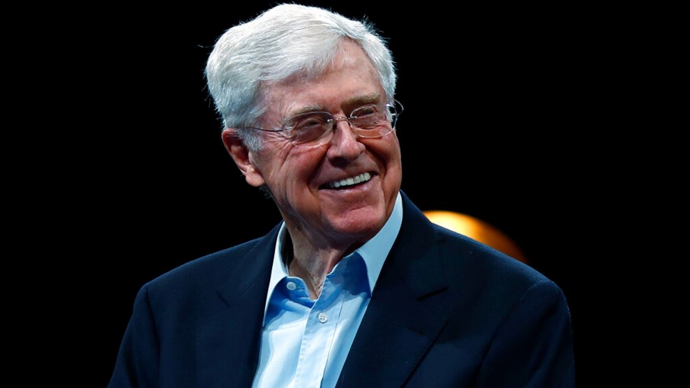 White man with blue shirt stands behind black background.