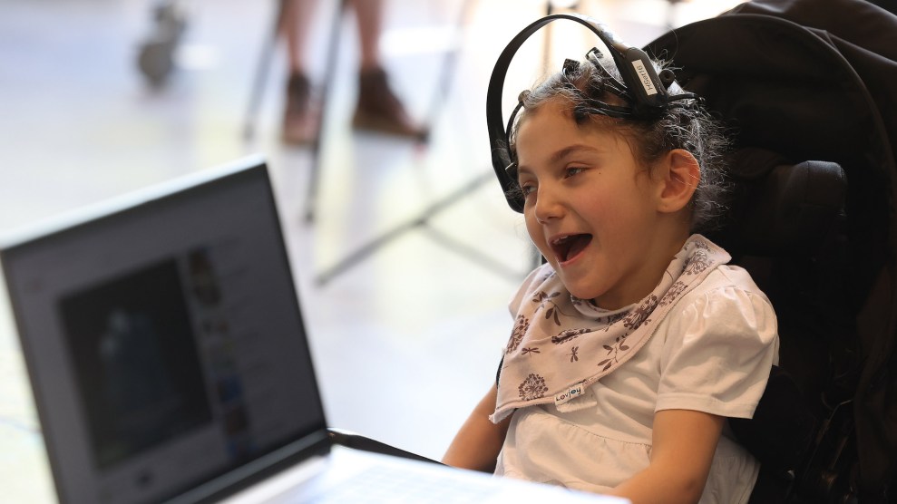 A white child wearing a device on their head with a computer next to them.