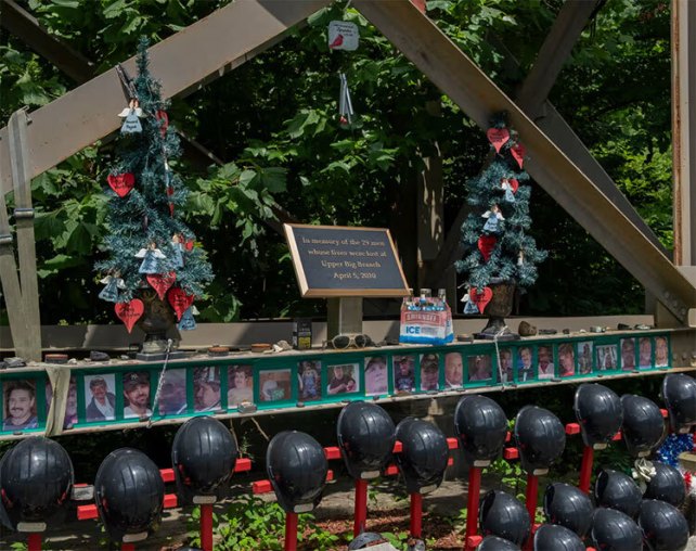 A memorial made of black helmets, a plaque, and photographs of miners.