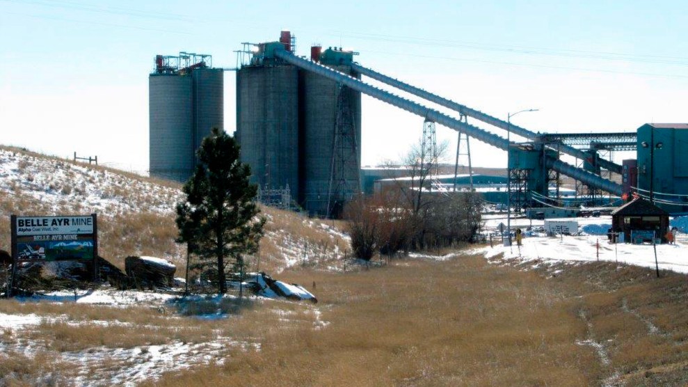 A coal mine and a factory, with, some snow on tge ground in front of it. There is also a sign that says "Belle Ayr Mine"