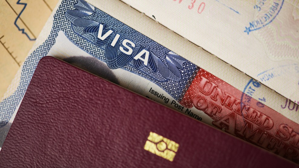 A maroon-colored passport on top of a United States visa