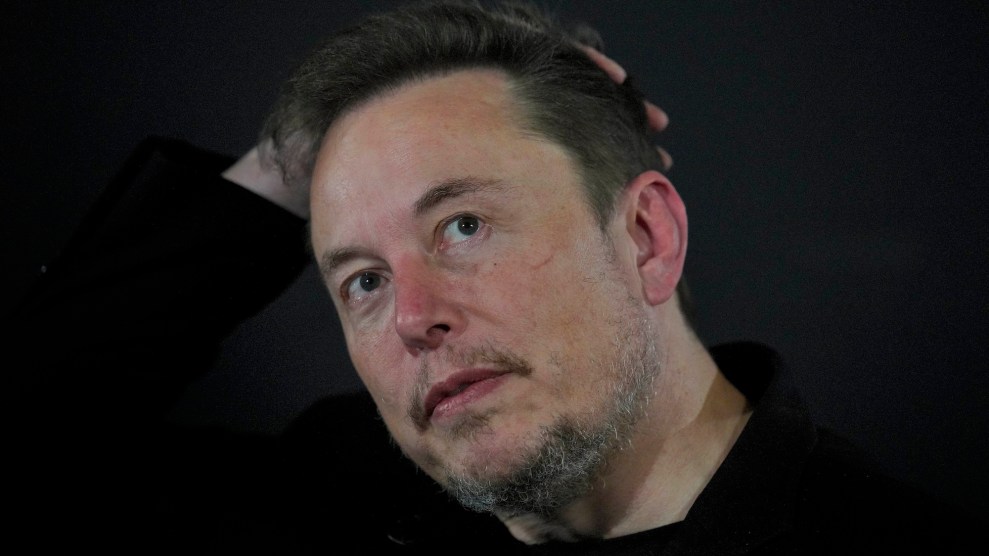 Elon Musk in a black shirt putting a hand on his head