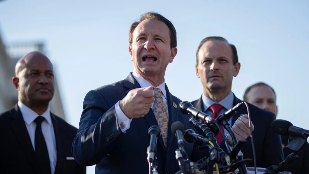 Jeff Landy, a white man, speaking into a microphone outside surrounded by three other men.