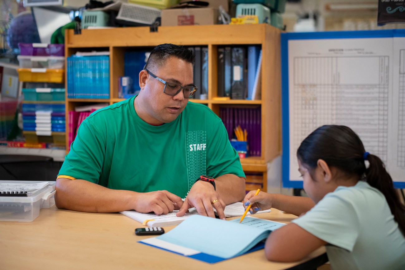 An education assistant works with a child on their homework at school.