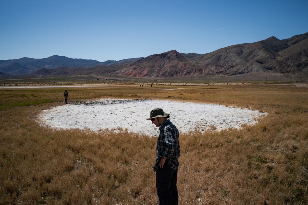 Two scientists looking at the ground in a mountainous desert region.