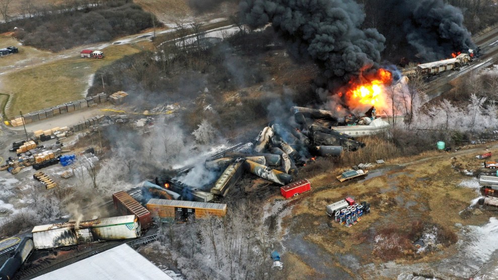 The image is crowded with smoke and train cars pressed together. There is an active fire in the upper right corner.