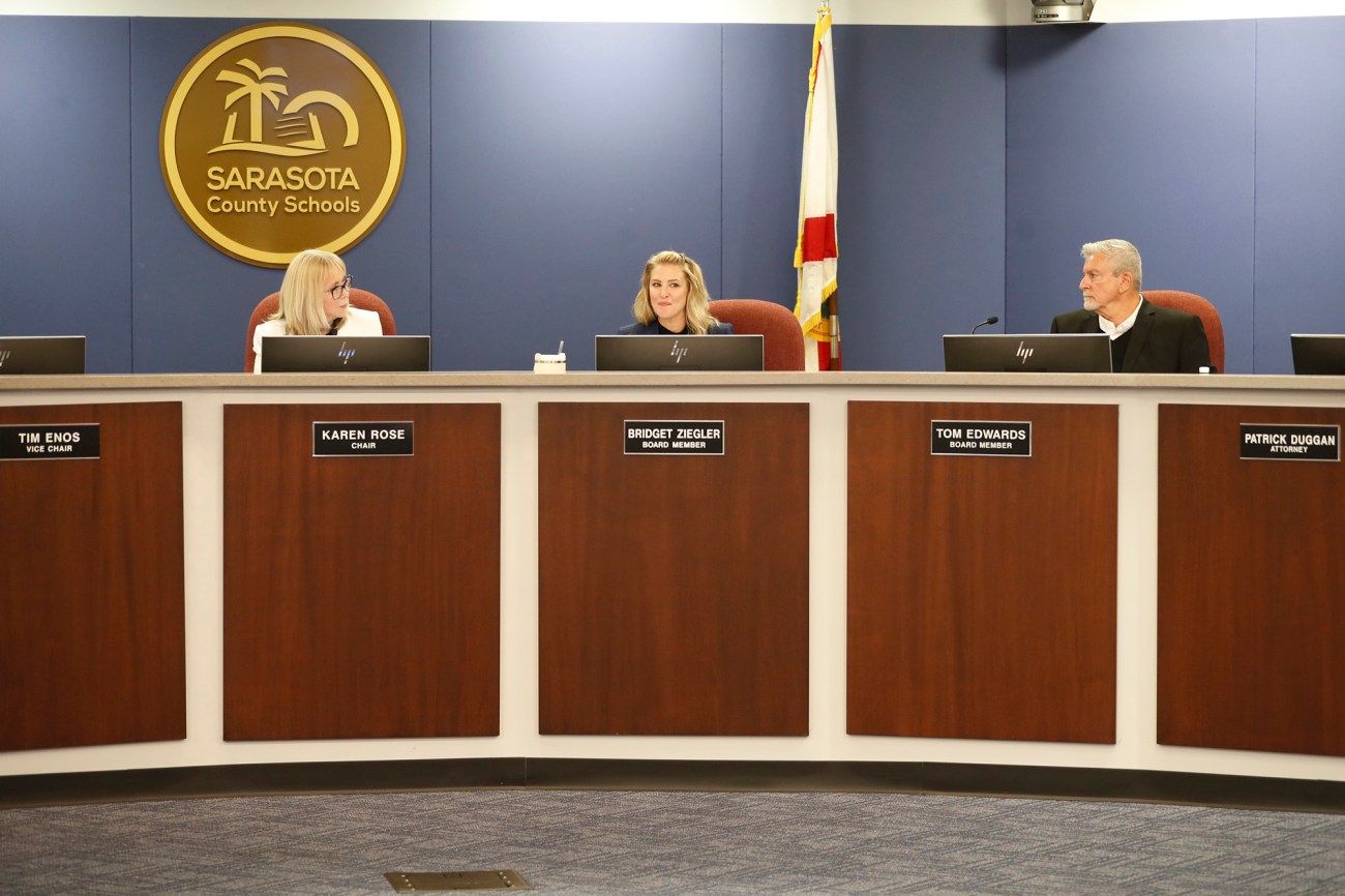 Three school board members – two women and one man – sit during a meeting.