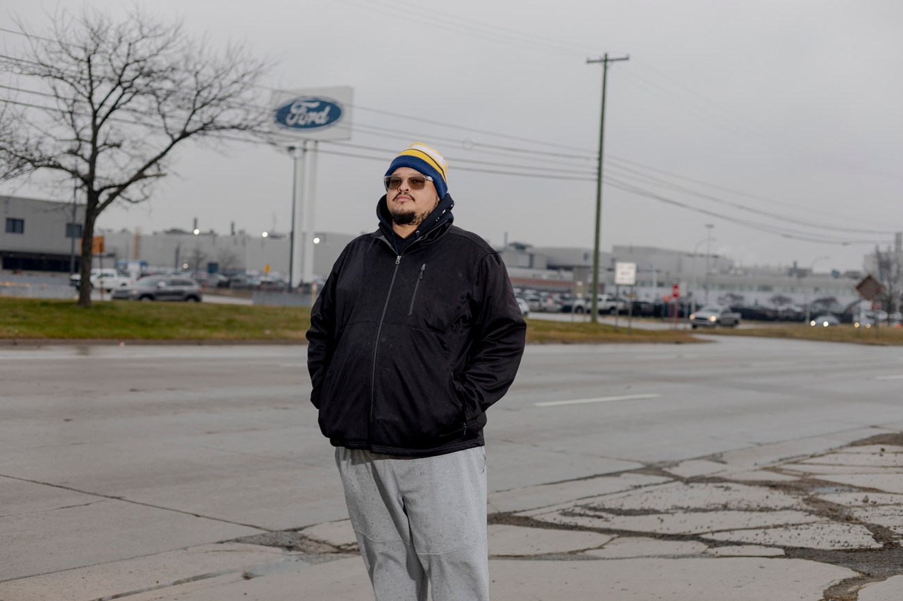 Portrait of a main with sunglasses on the street in front of a Ford building.