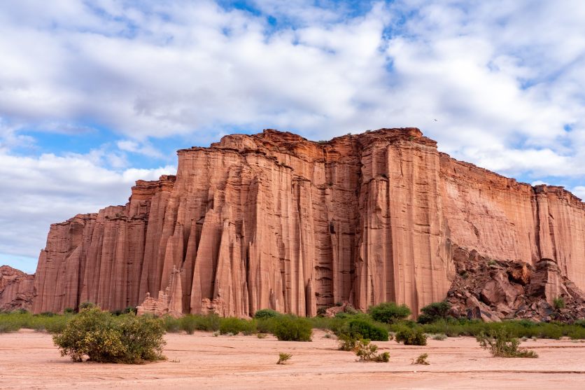 A big orange rock formation in front of a cloudy sky.