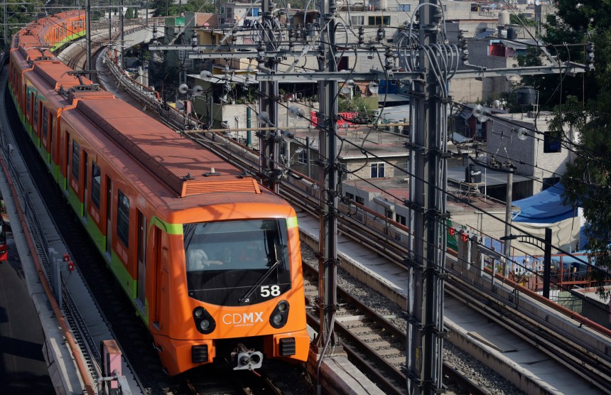 An orange metro rain curves through a dense city.