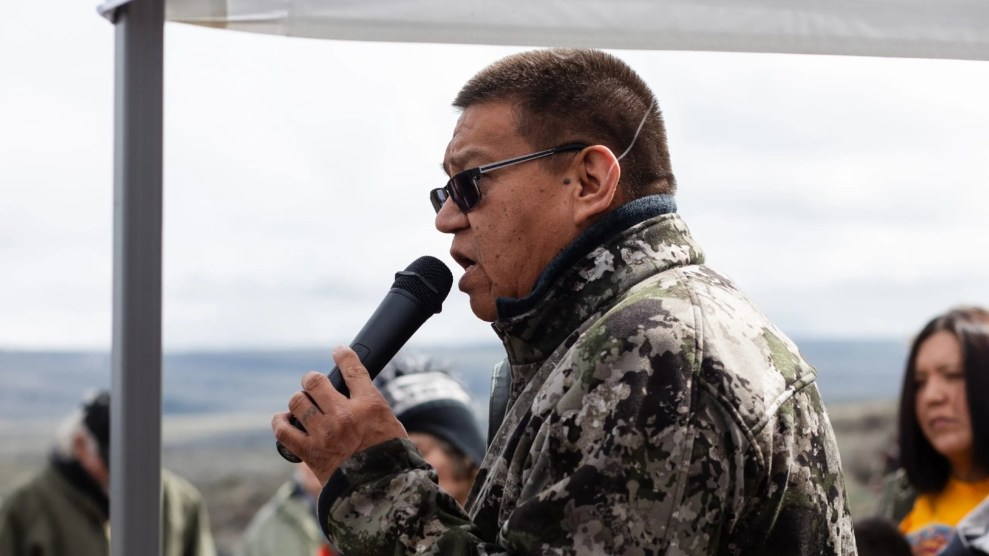 A man with close-cropped black hair speaks into a microphone.