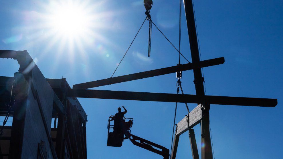 A construction worker under a blue sky and a sun, looks hot out