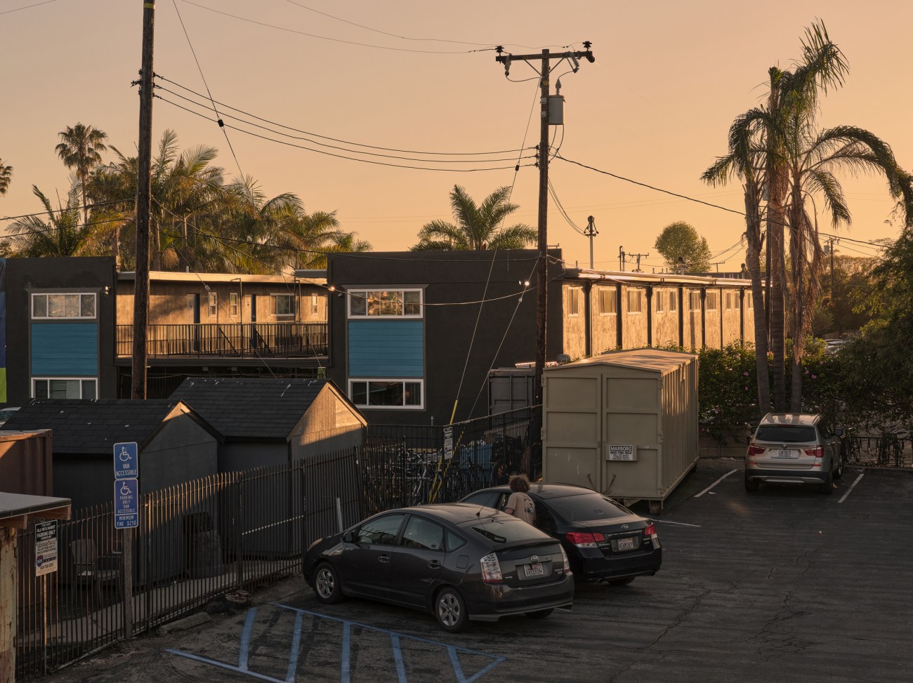 Dusk view of an apartment building and parking lot.