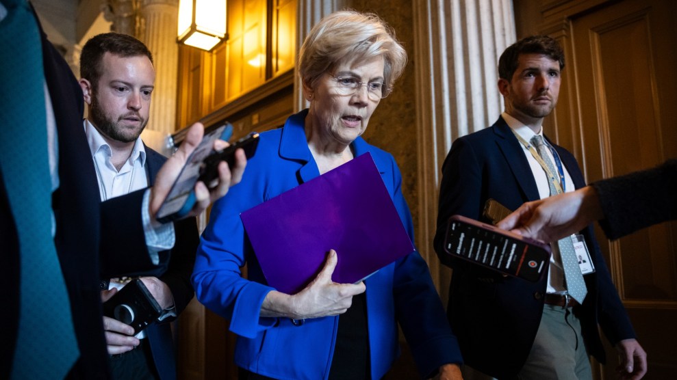 A white women with short blond hair and a blue coat walks, flanked by two individuals with short brown hair and stubble.