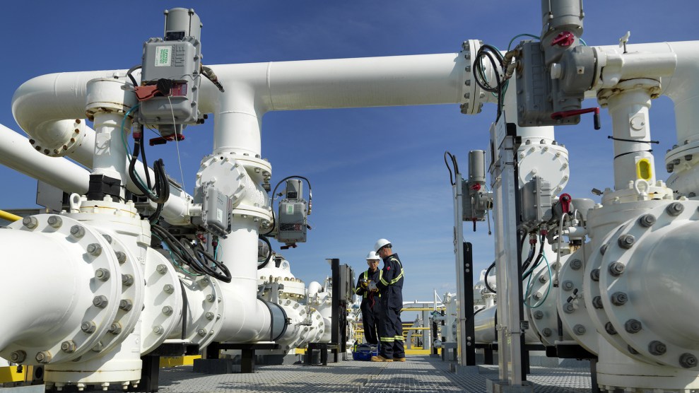 Two workers stand between white machinery outside