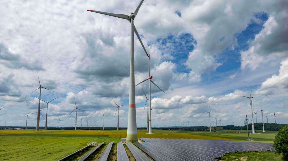 A wind farm with solar panels on the ground