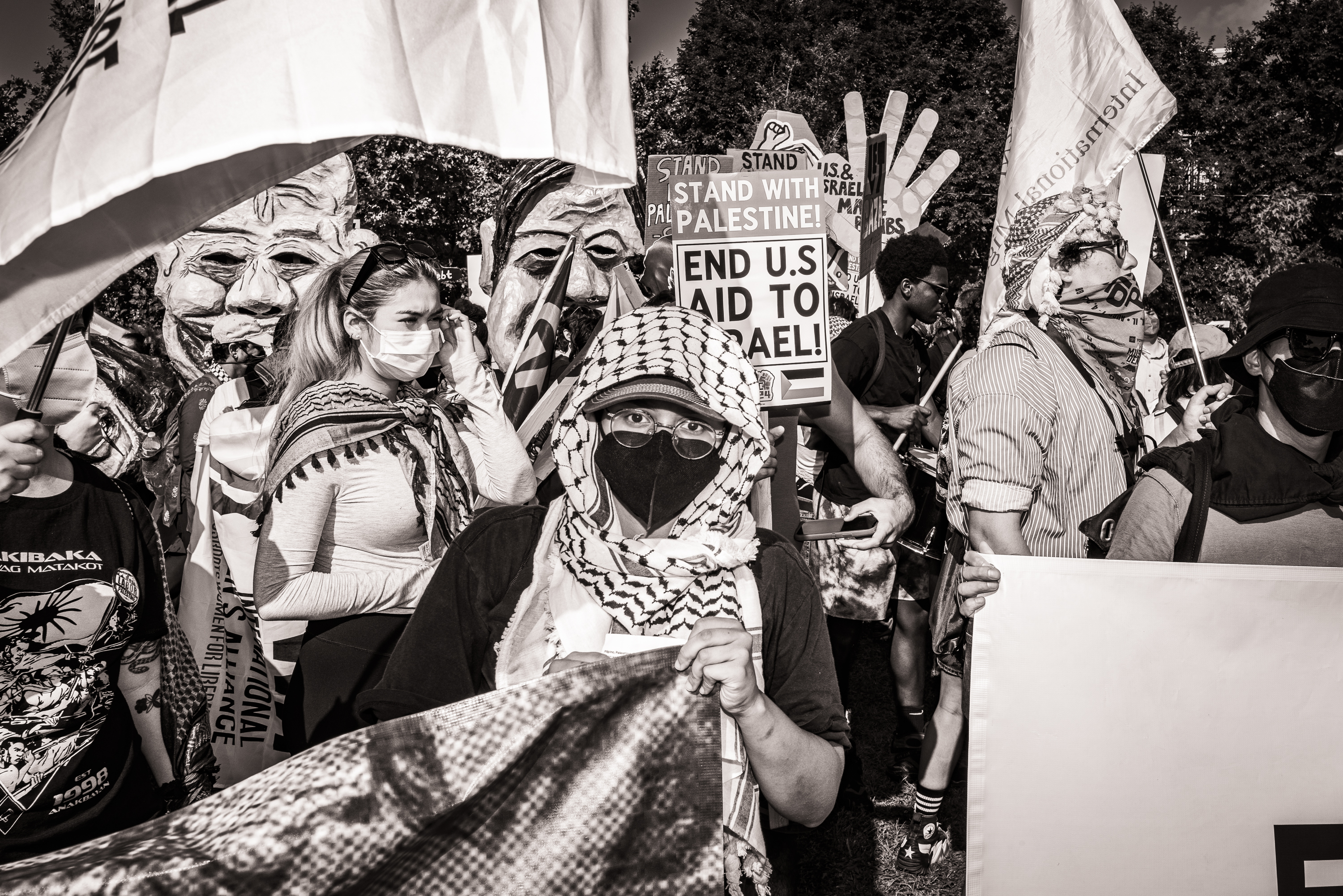 Black and white photo of a protester wearing a hijab, looking at the camera during a protest.