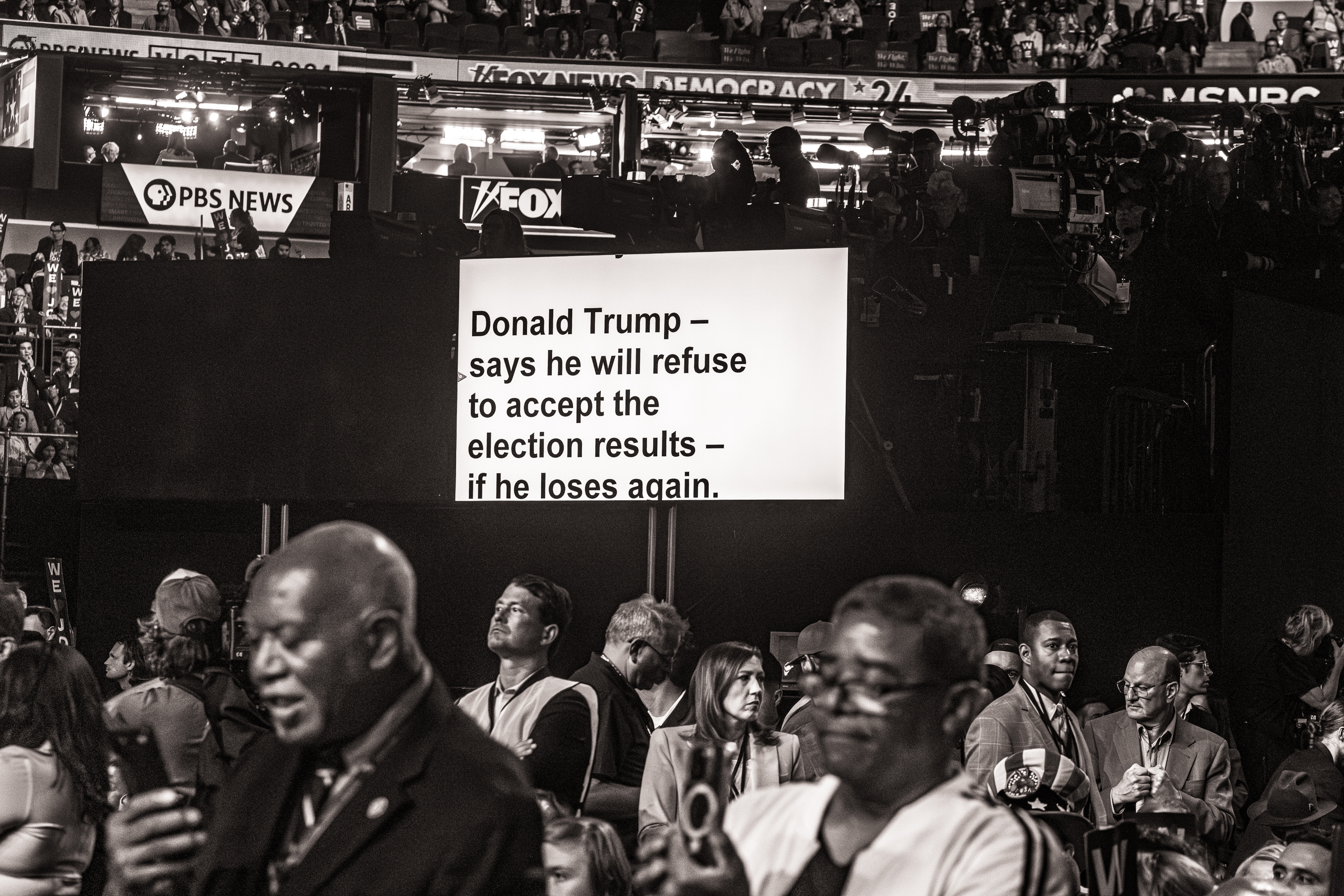 Black and white photo of of a teleprompter that reads, "Donald Trump says he will refuse to accept the election results if he loses again."