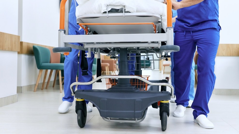 Medical staff push a gurney in a hospital hallway.