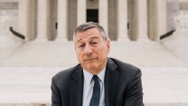 Man in suit and tie sitting on steps in front of the U.S. Supreme Court