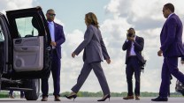 Harris walks over an airport tarmac toward an open limousine door.