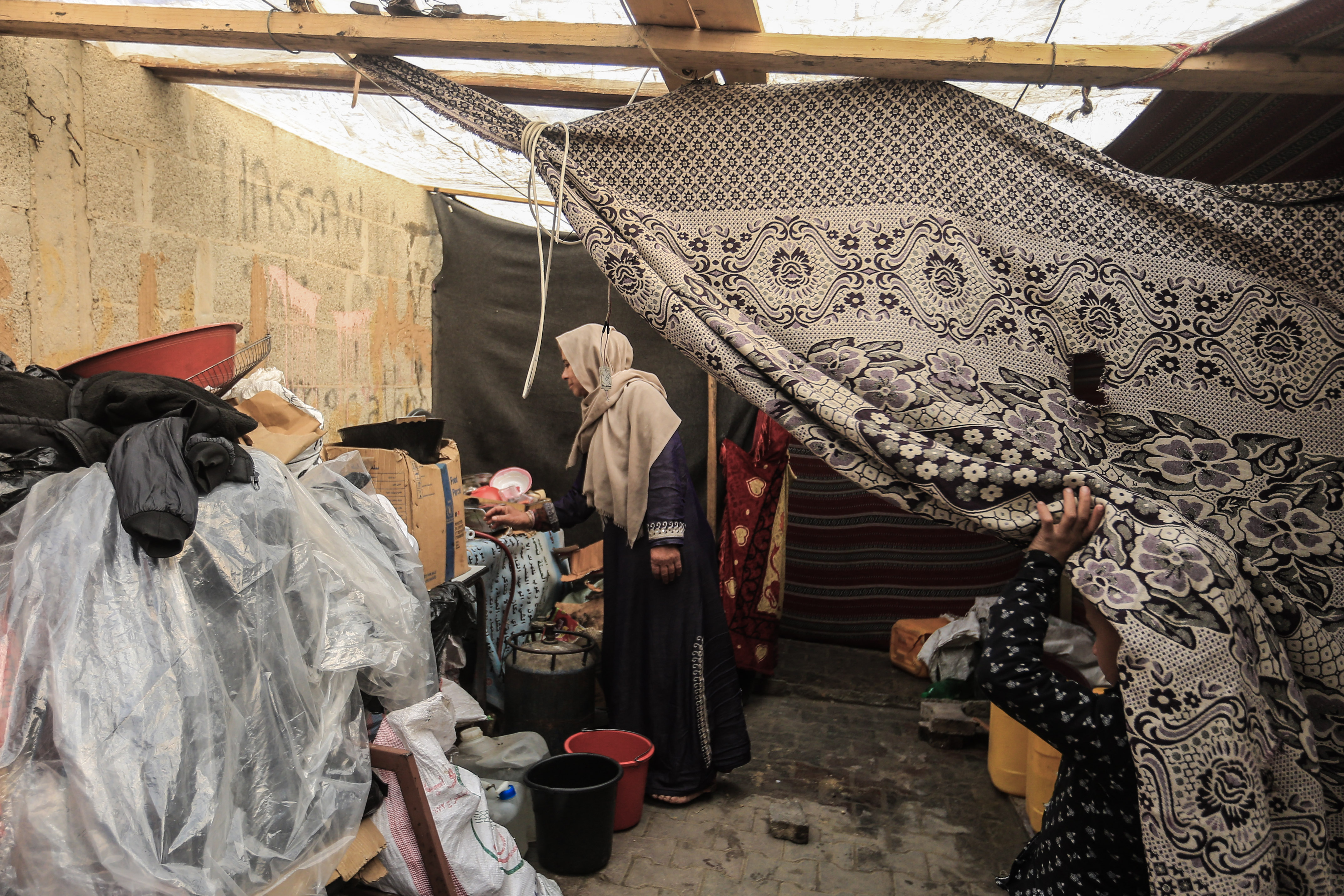 Curtains hang as a partition in a temporary tent that houses Palestinian refugees.