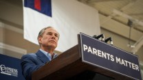 Greg Abbott stands on a podium with a sign that reads, "Parents matter."