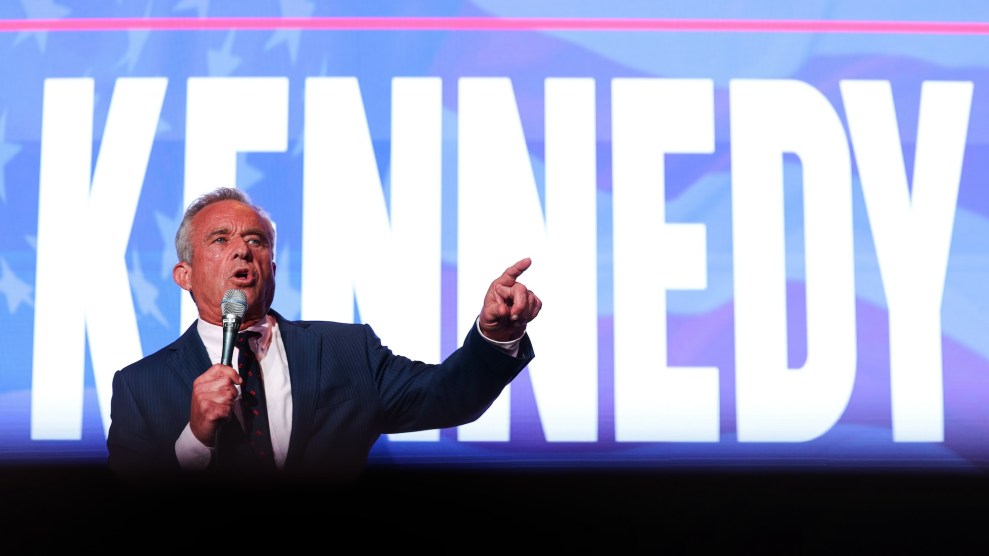 RFK Jr. speaking into a microphone with a background that says "Kennedy" behind him