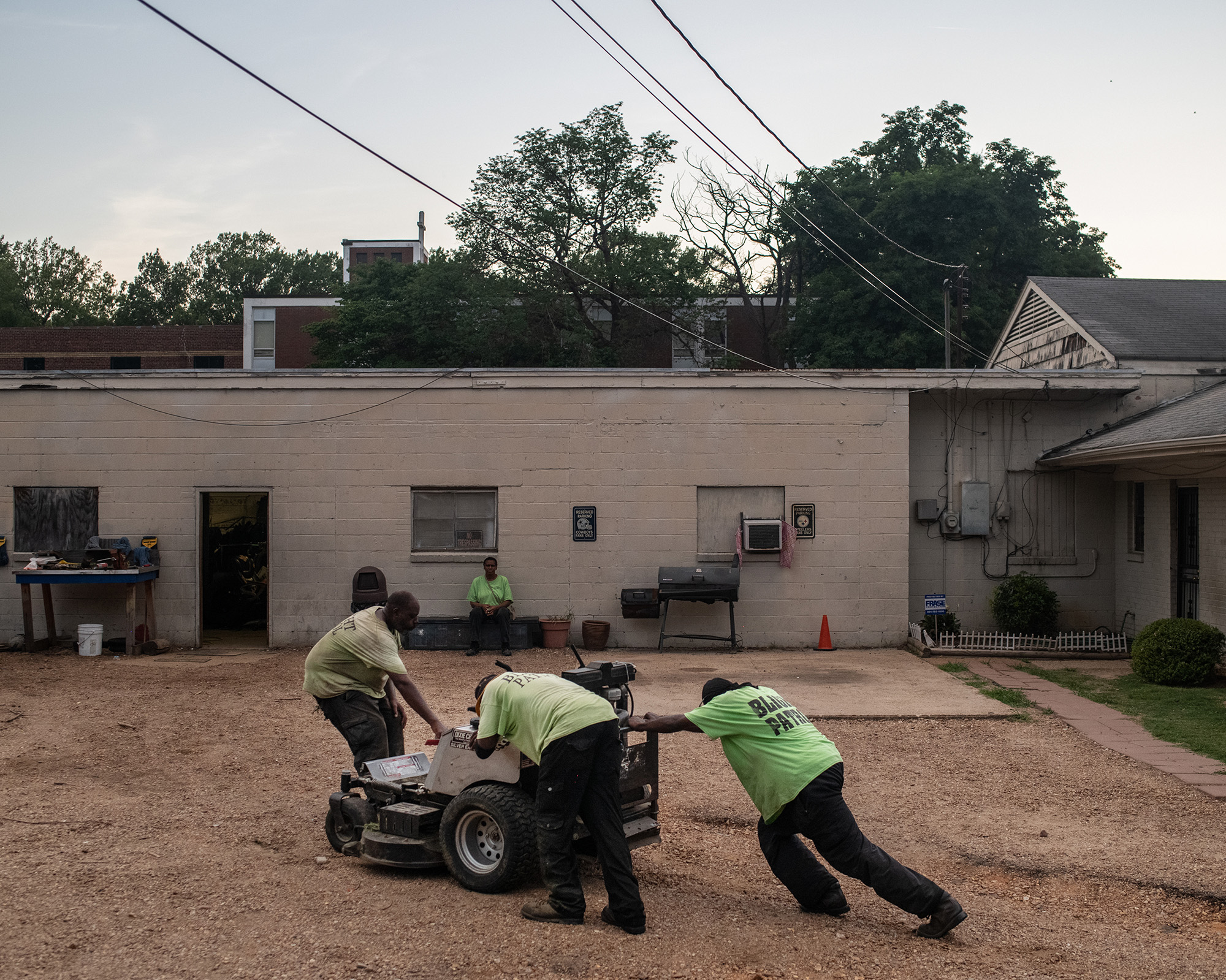 Three men push a piece of machinery.