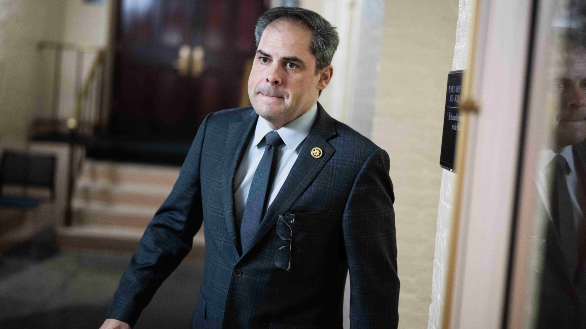 Rep. Mike Garcia walks out of a meeting into a hallway. 