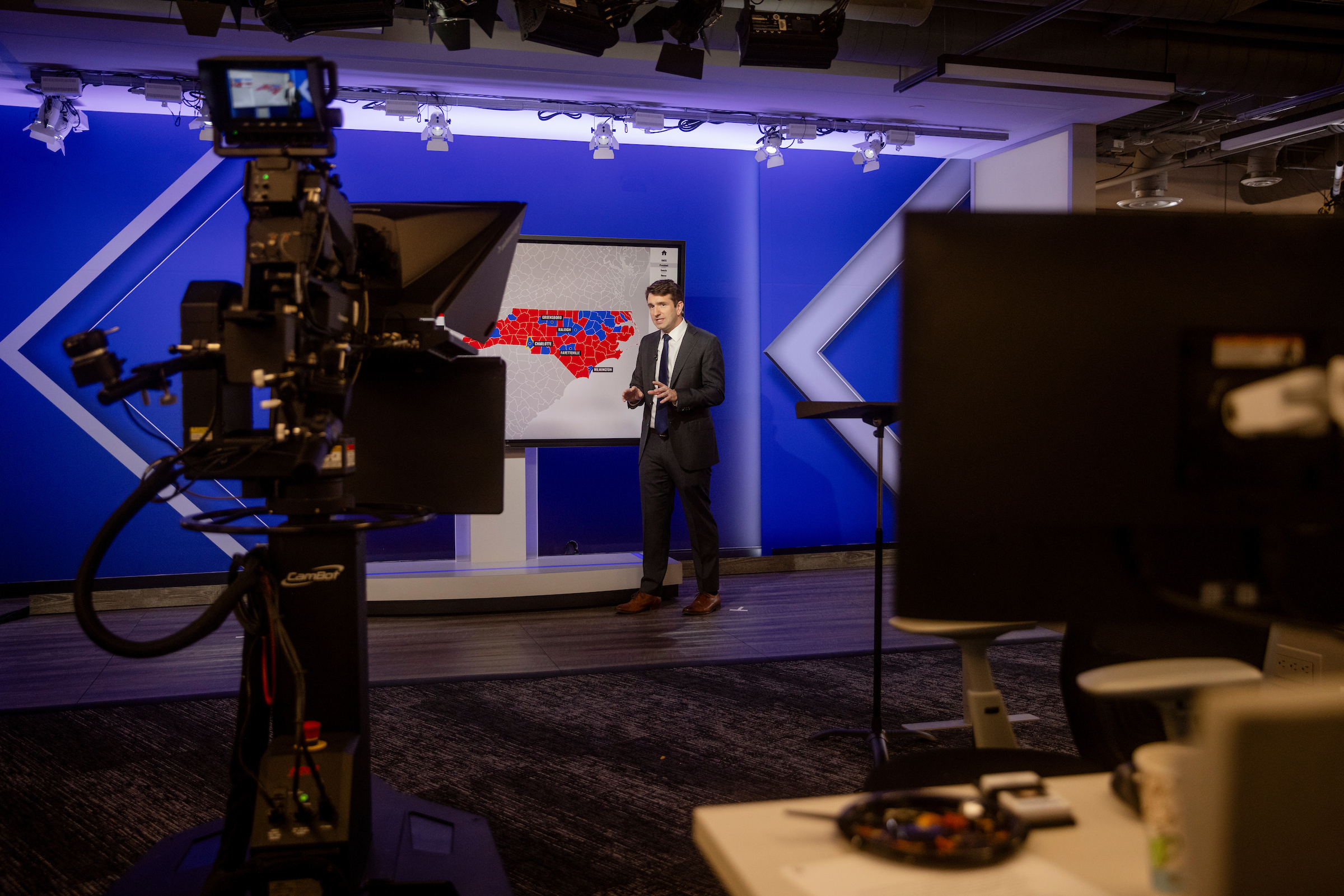 Man standing in front of a screen in a television studio.