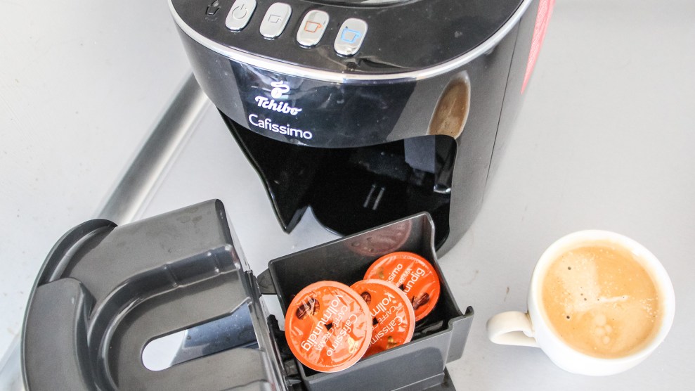 An instant coffee machine with used orange coffee cups and a lattee.