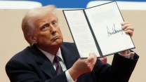 President Donald Trump holds up an executive order after signing it.