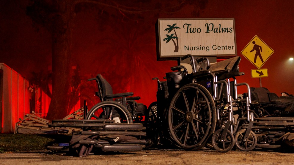 A sign that says "Two Palms Nursing Center" with a bunch of wheelchairs in front of it outside. The sky is red due to a wildfire.