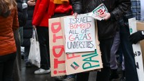 A student holds a sign reading "Israel bombed all of Gaza's universities."