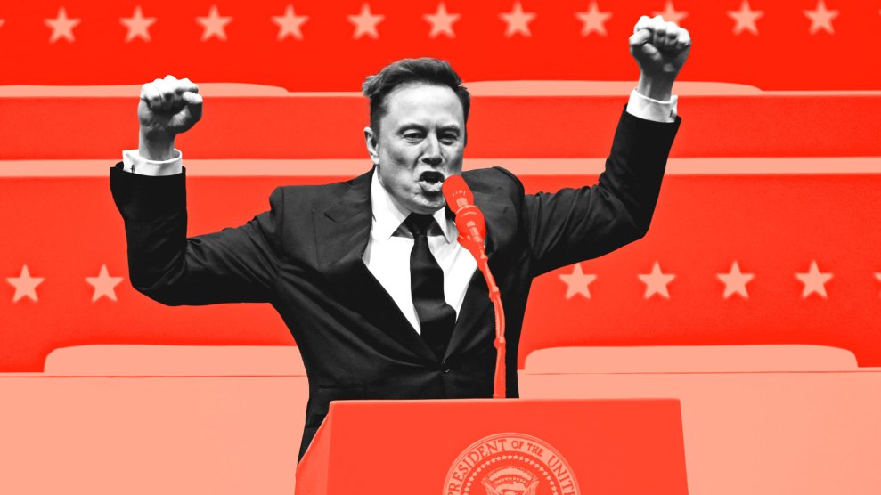 Elon Musk, in black and white dressed in suit in tie, raises both his fists in the air as he stands in front of the presidential lectern. Musk appears to be speaking aggressively into the microphone, in front of a backdrop of stars. The background and the lectern in front of Musk are bathed in shades of dark and light red.