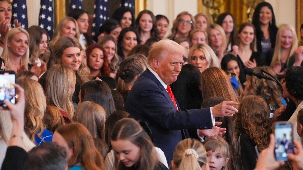 Donald Trump stands in the middle of a large group of women, most of them young.