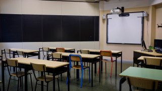 An empty classroom with desks, a white board and a chalk board