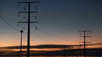 Two power lines stand tall as the sunsets behind them