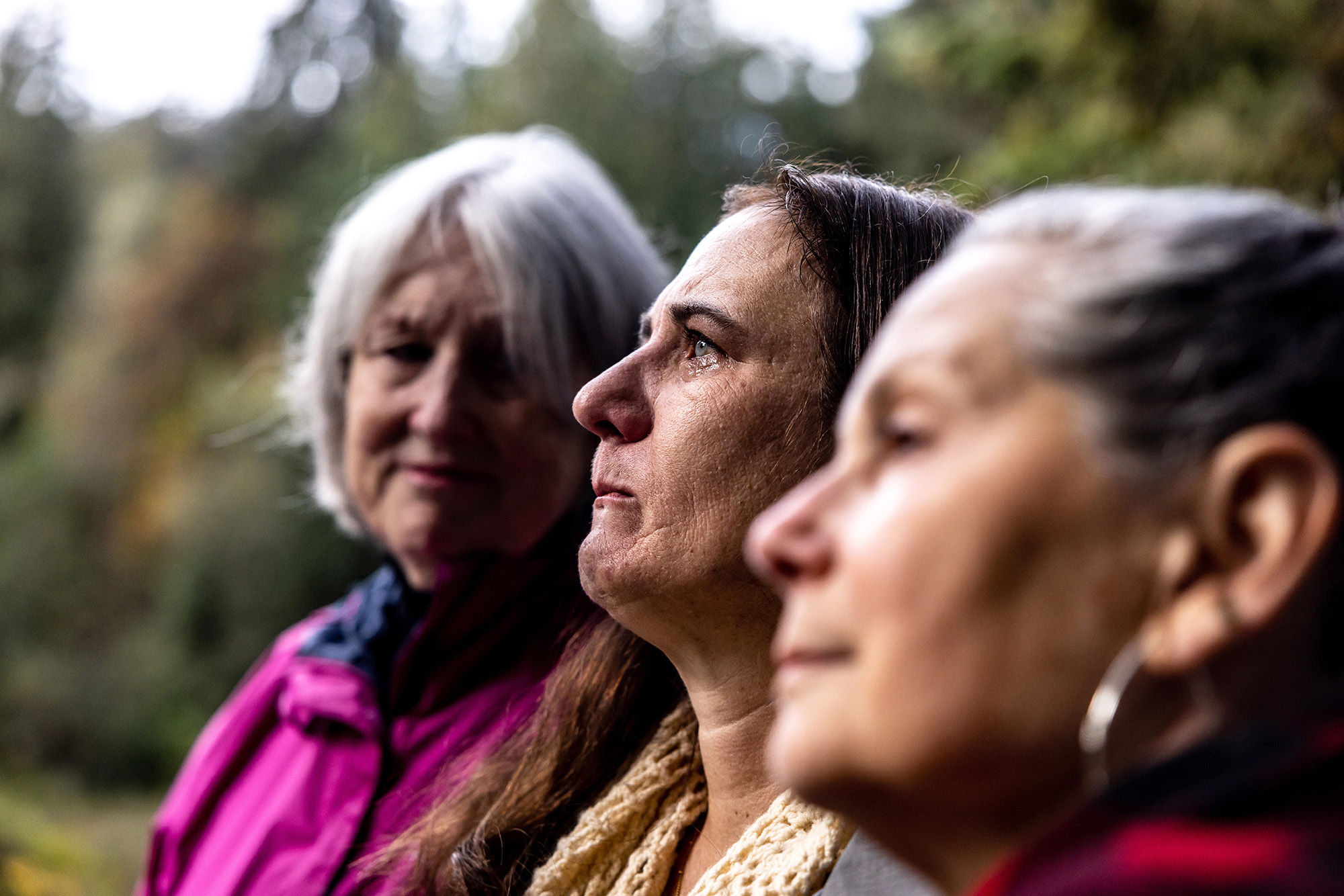 Three woman standing side by side outside.