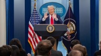 A white man stands at a podium next to an American flag.