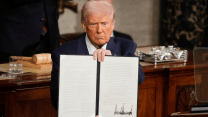 President Donald Trump holds up a signed executive order in front of the joint session of Congress on Tuesday, March 4, 2025.