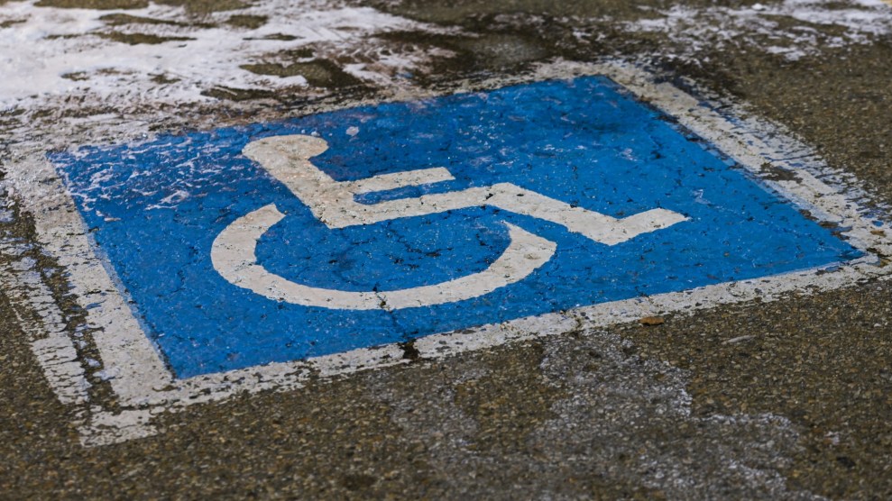 A wheelchair parking symbol on a parking spot on the pavemont with some snow on top of it.